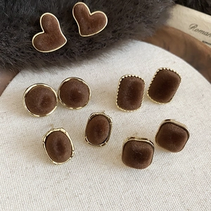 Detailed view of dark brown flocked geometric stud earrings with gold metal borders