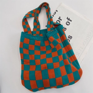 Close-up of blue and orange checkered knit tote bag on a fashion magazine background