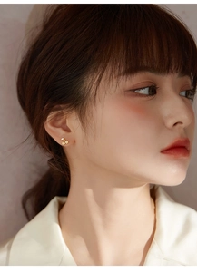 Close-up of model wearing delicate cherry earrings with crystal inlay and gold finish