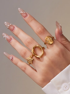 Detail of three-piece gold-plated geometric ring set with zircons and star patterns