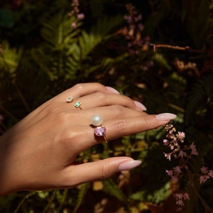 Detailed view of 18K gold plated rings set with pink gem, pearl and green crystal