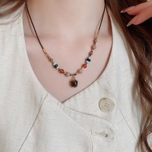 Detail of bohemian tiger eye stone pendant necklace on model in warm earth tones