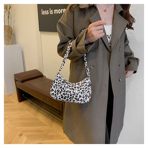 Détail du sac à bandoulière léopard avec sangle assortie porté sur un trench beige
