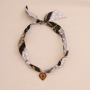 Close-up of heart pendant necklace featuring silk scarf with polka dots and golden chain link