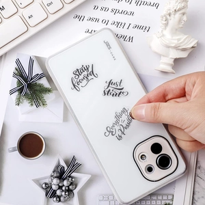 Transparent iPhone case with motivational English quotes stickers on a desktop background