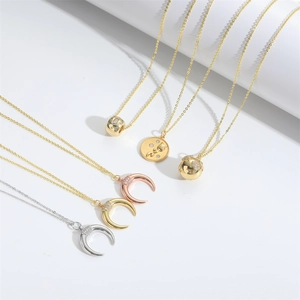 Close-up of crescent moon and coin pendants with sparkling crystals on fine chains