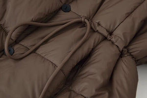 Détail de la veste matelassée marron avec taille à cordon et boutons ronds noirs