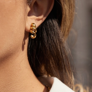 Gros plan de boucles d'oreilles spirales dorées sur modèle avec élégante texture torsadée