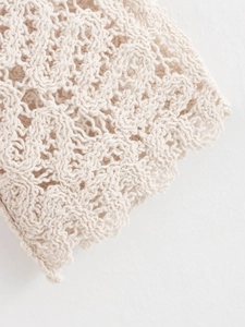 Primer plano detallado del vestido de punto crema con intrincados motivos florales calados