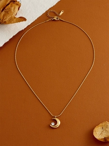 Macro shot of a gold crescent moon necklace with clear zircon pendant on brown leather