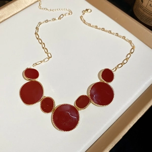 Détail d'un collier vintage doré avec pendentif composé de cercles en émail rouge superposés