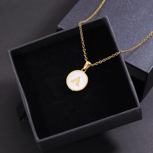 Close-up of golden shell pendant with letter A displayed in a black jewelry gift box