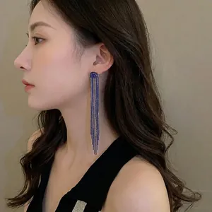 Elegant long dark blue fringe tassel earrings with golden top worn by a fashion model