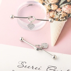 Detailed view of stainless steel industrial barbell featuring a crystal heart dangle charm