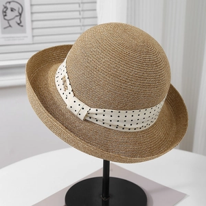 Detailed view of woven straw sun hat featuring a polka dot ribbon and metal logo detail
