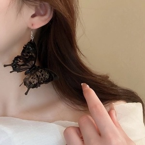 Gothic style black acrylic butterfly hook earring worn by model in a close-up profile view