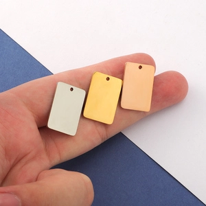 Three rectangular stainless steel blank tags in silver, gold and rose gold on a finger