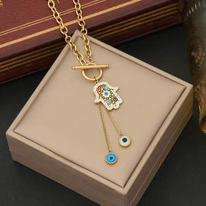 Vue détaillée du pendentif main de fatma doré avec charms œil grec et fermoir en T