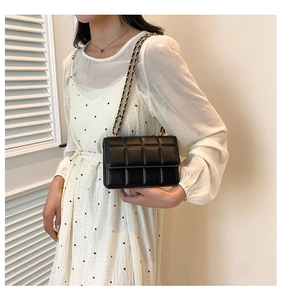 Detail of black quilted PU leather crossbody bag with elegant metal chain shoulder strap