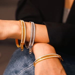 Zircon zipper bangles in gold and silver finish on wrist with punk-style design