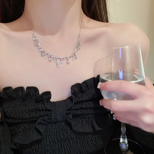 Detail of silver branch necklace with sparkling teardrop pendants on model's collarbone