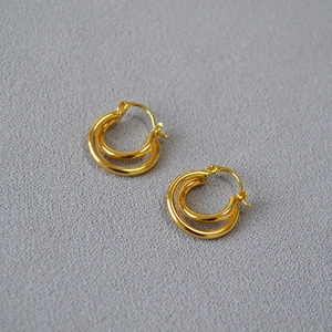 Detail view of gold-plated double-hoop earrings featuring a twisted metal texture