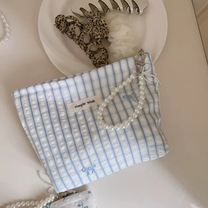 Detail of blue plaid cotton pouch with pearl handle chain and bow embroidery