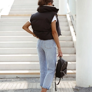 Outdoor back view of a black quilted puffer vest paired with casual jeans and a backpack