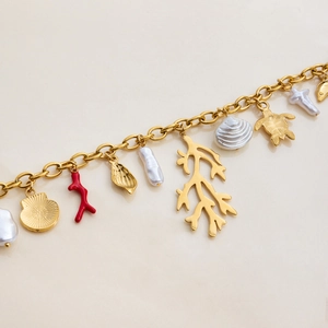 Detailed shot of gold-plated ocean charms with sea turtle and shell on a metal chain