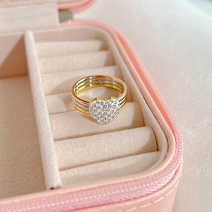 Detailed view of stacked tricolor rings with micro-paved heart shaped zircon in a jewelry box