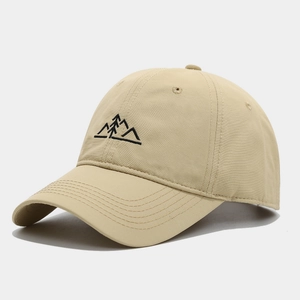 Détail d'une casquette de baseball beige avec broderie fine de montagnes et de forêt
