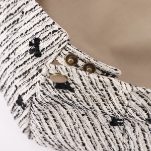 Detailed close-up of tweed fabric texture and vintage bronze metal button on the hat