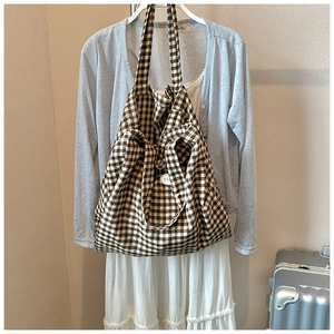 Detail of a plaid tote bag in coffee and beige hanging with casual travel outfits