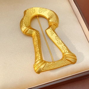 Macro shot of vintage gold keyhole brooch with granular texture on silk lining