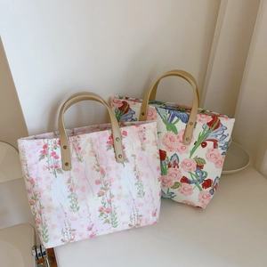 Detailed close-up of floral tote bags with leather handles and metallic rivet accents