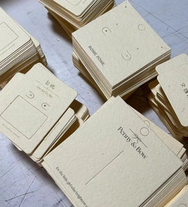 Detailed view of stackable cream paper jewelry display cards with hanging holes