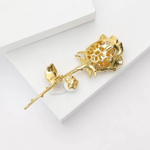 Detail of vintage gold rose brooch with sparkling crystal inlay on white background