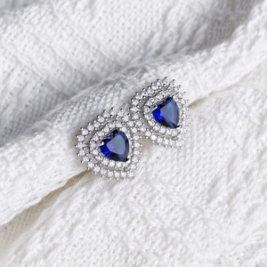 Macro shot of heart-shaped earrings with deep blue gemstones and pavé set white crystals