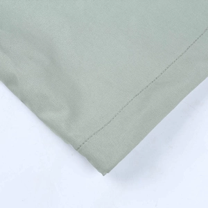 Vue macro montrant les coutures fines et la texture du tissu vert clair de ce pantalon
