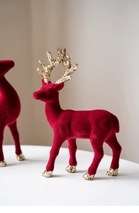 Macro view of burgundy flocked Christmas reindeer ornament with sparkling gold glitter details