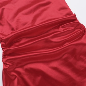 Close-up of elegant red satin fabric with textured ruching detail on evening dress