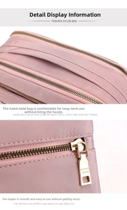 Detailed view of pink nylon crossbody bag featuring gold zippers and reinforced handles