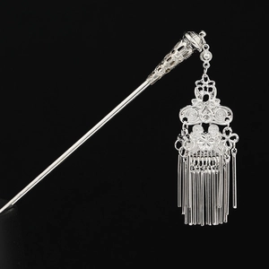 Macro shot of silver Miao hair stick featuring intricate filigree design and dangling tassels