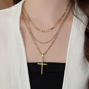 Close-up of layered 18k gold plated chains with cross pendant on model neck
