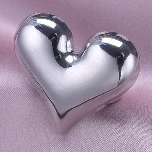 Detailed view of silver heart-shaped ring on pink silk fabric showing high reflective finish