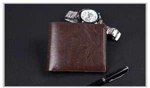 Short brown leather wallet with vintage texture displayed with a pen and watch