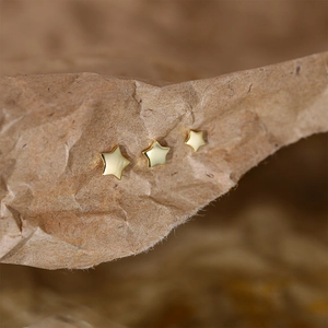 Macro shot of three gold star stud earrings in different sizes on kraft paper
