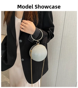 Silver spherical evening bag with metal ring handle and gold chain worn by a model