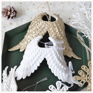 Detail of glitter gold and matte white angel wing ornaments with sparkling finish