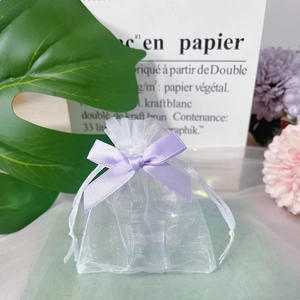 Detail of white organza gift bag featuring a purple satin ribbon drawstring and bow